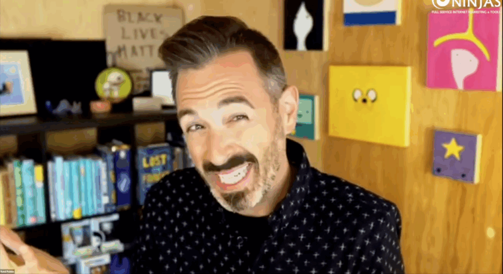 Man with dark hair and beard gestures while speaking on a video call about product-driven seo, with colorful art and books behind him—a scene reminiscent of rand fishkin’s sessions for seos.